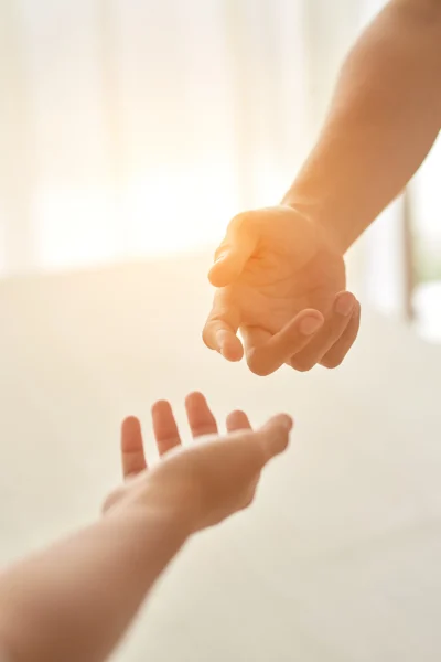 hands-couple-extended-each-other-against-sunlit-room